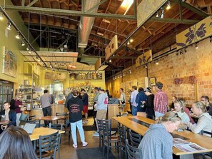 A busy cafe with wooden tables and chairs, a counter with staff, and brick walls. - Era & Edge | 3BR Victorian at 9th & 9th, Yard, Dog (Salt Lake City)
