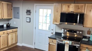 A kitchen with wooden cabinets, a microwave, an oven, and a black countertop. - FREE NIGHT•KNOTTY ESCAPE• Hikers Haven in RRG• Walk to Attractions • Hot Tub• (Campton)