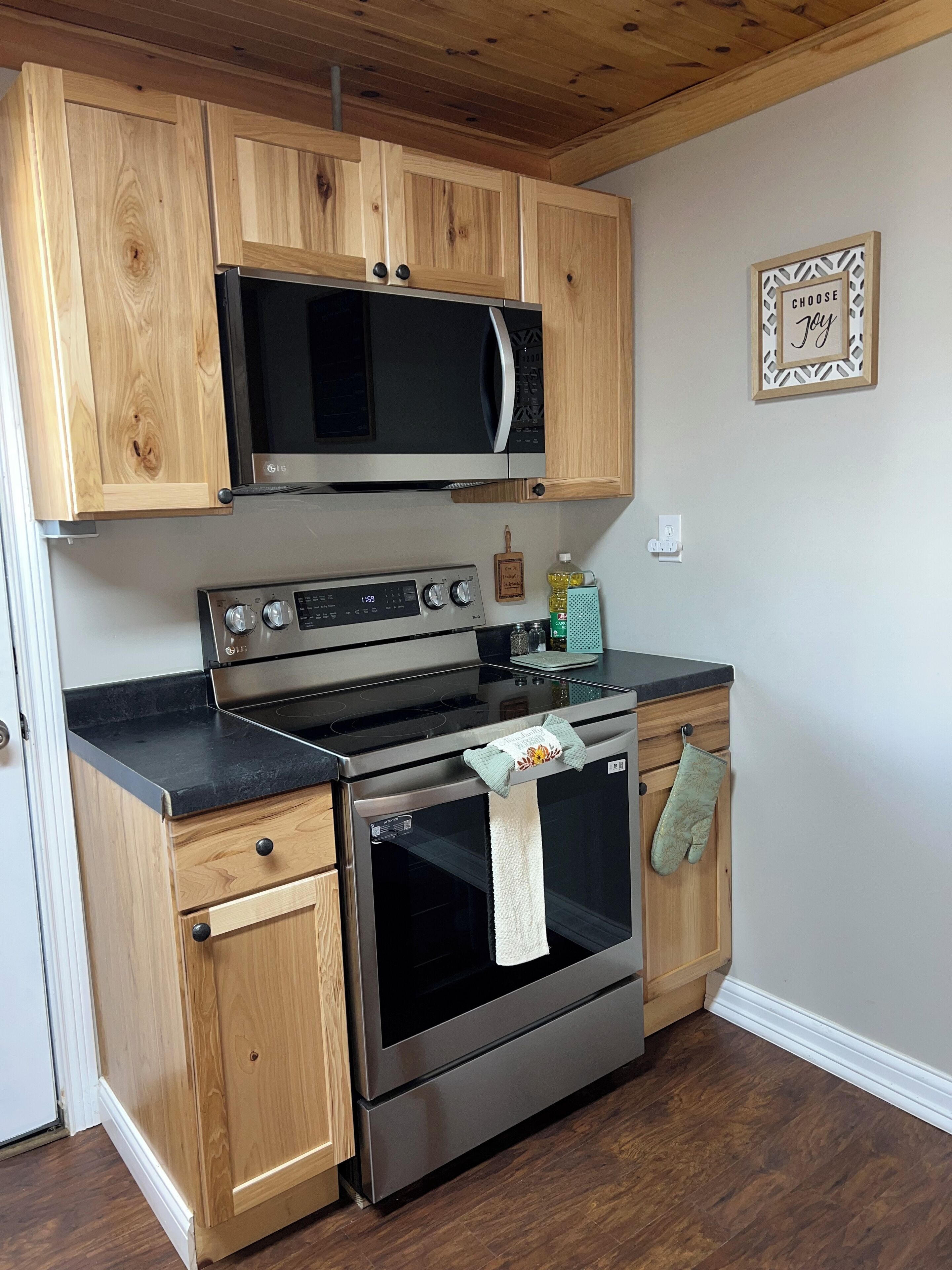 A kitchen with wooden cabinets, a microwave, an oven, and a stove.