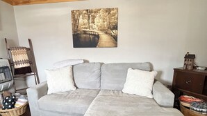 A room with a wooden ceiling, a gray sofa with white cushions, a wooden floor, and a painting of a forest path. - FREE NIGHT•KNOTTY ESCAPE• Hikers Haven in RRG• Walk to Attractions • Hot Tub• (Campton)