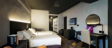 Habitación de hotel con cama, escritorio, silla, lámpara de escritorio, televisor de pantalla plana y cafetera.