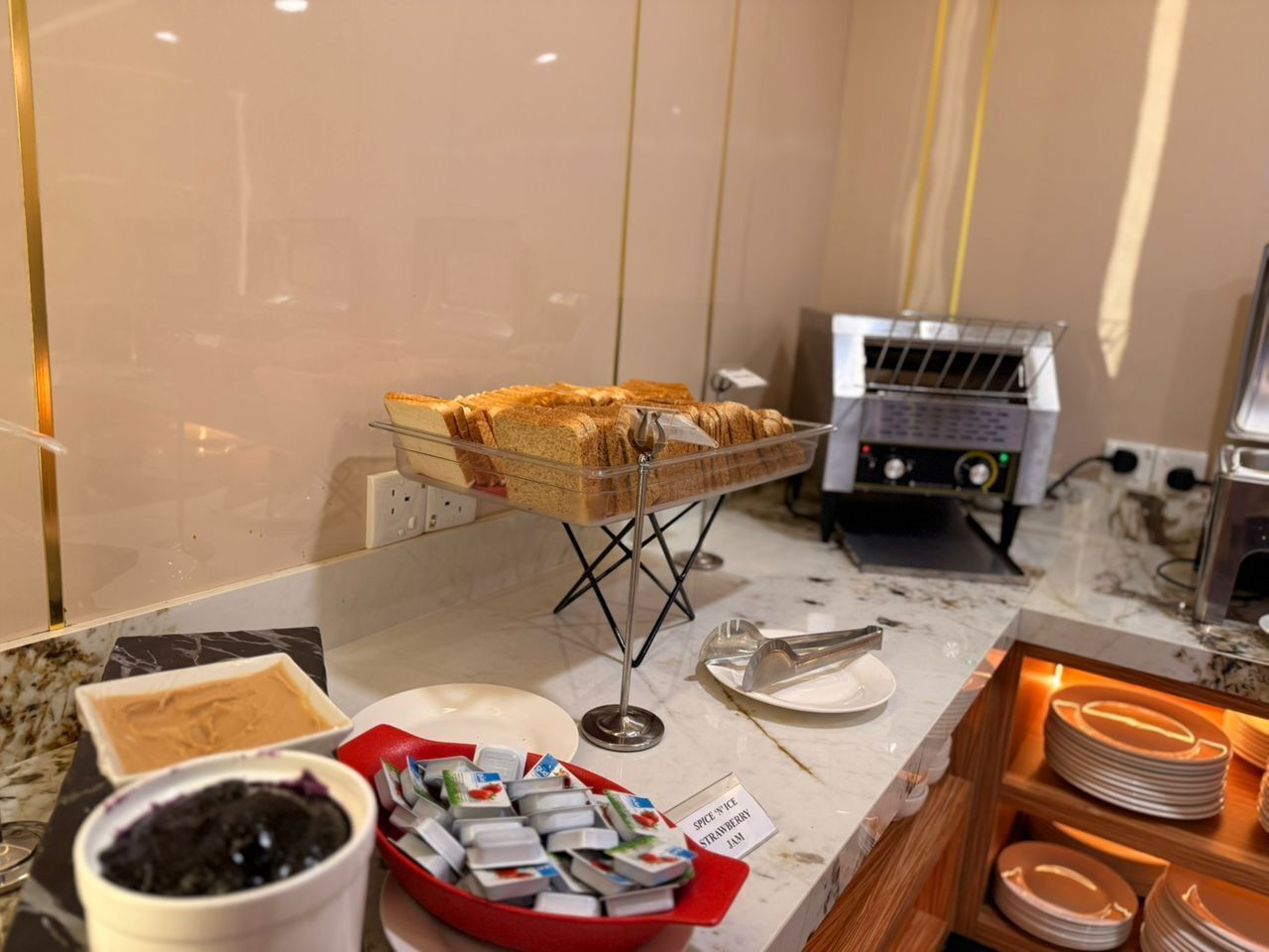 A buffet setup with sandwiches, a coffee machine, and a variety of condiments.