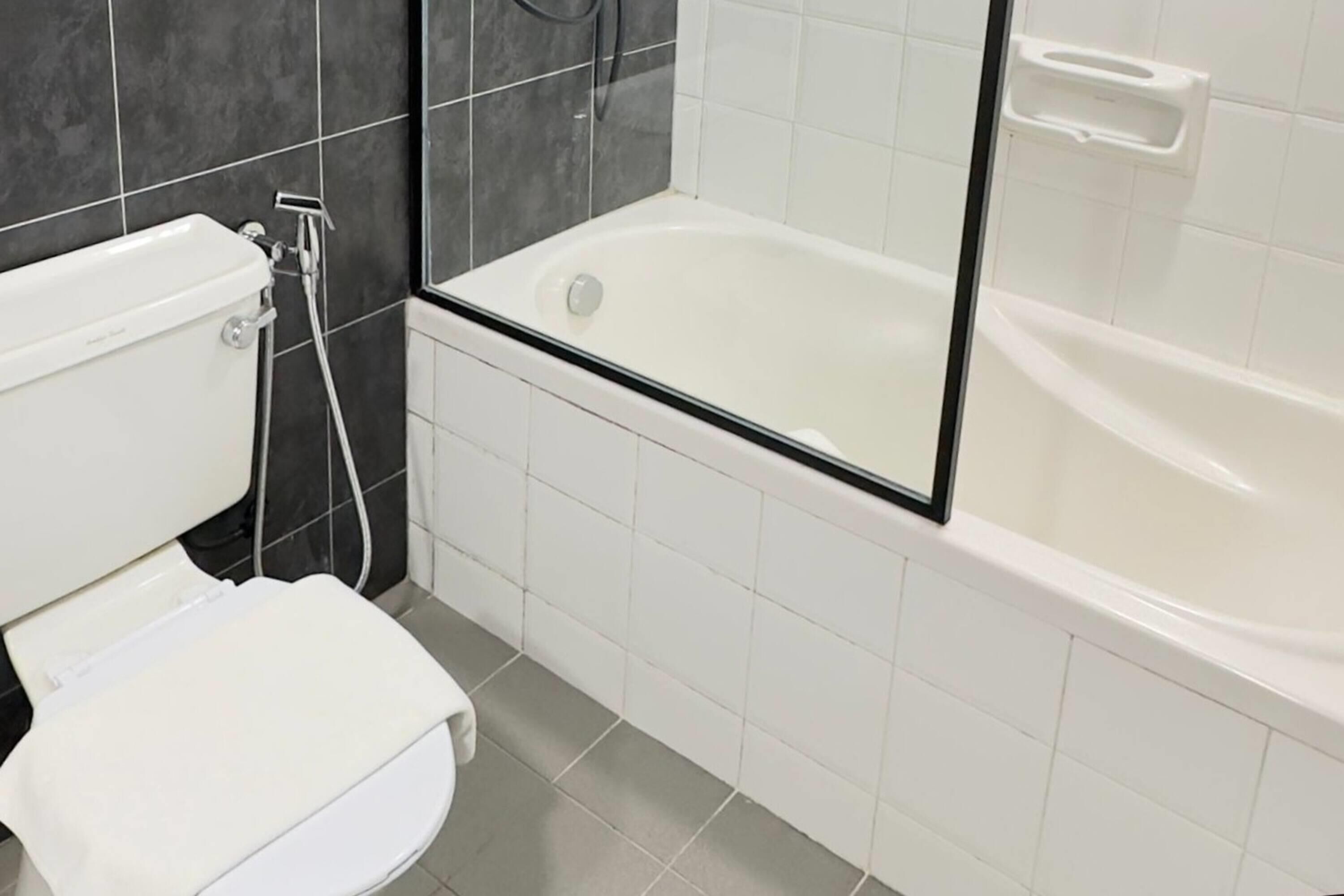 Een badkamer met toilet, bad en douche.
