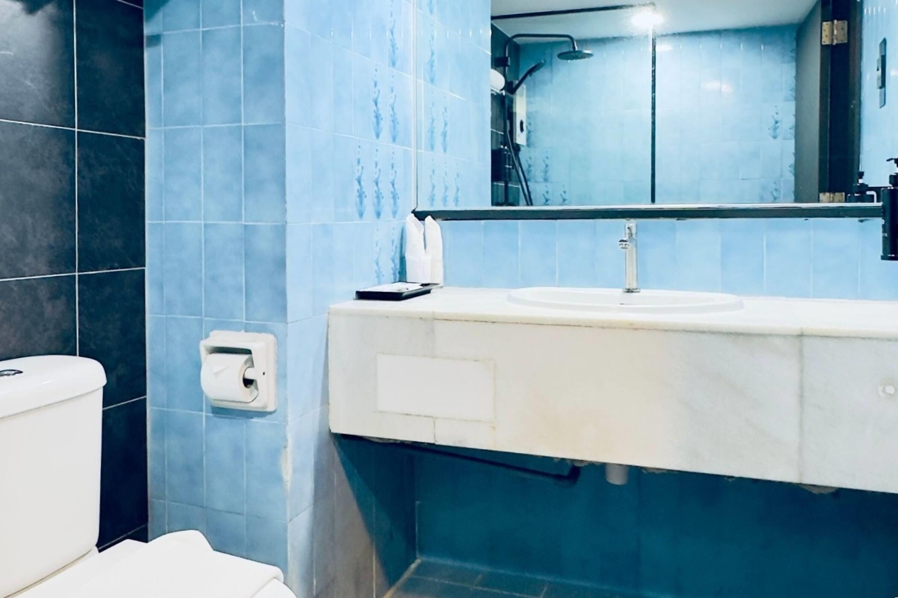 A bathroom with a white toilet, a sink, and a mirror above it.