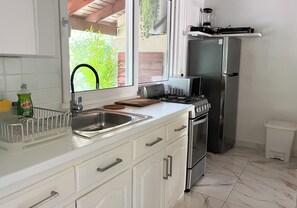Une cuisine équipée d’un réfrigérateur, d’une cuisinière et d’un évier en acier inoxydable.