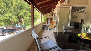 A balcony with a chair, a table with fruit, and a hanging chair.