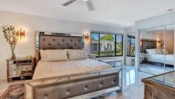 Une chambre à coucher moderne avec un grand lit, un ventilateur de plafond et une vue sur l’extérieur.