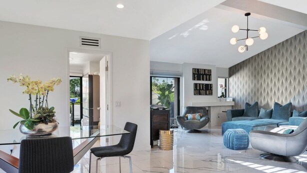 A modern living room with a glass dining table, black chairs, a blue sofa, and a decorative wall piece. - Luxury Retreat ✨ Views, Heated Pool+ Spa Baths.♥️smart bidet (Palm Desert)
