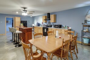 Una cocina con una mesa de comedor, sillas, un refrigerador y un microondas.