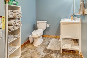 A bathroom with a toilet, sink, and shelves with towels. - 1 Mi to Greers Ferry Lake! Outdoor Adventure Base (Higden)