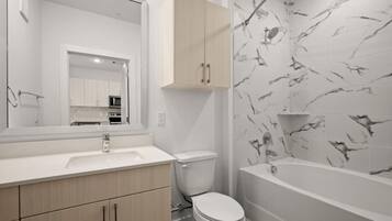 A modern bathroom with a toilet, sink, and bathtub.