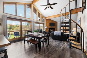 A spacious living area with a dining table, chairs, a sofa, and a staircase. - On 18th green @ shanty creeks Schuss Mtn - Sleeps 8 (Mancelona)