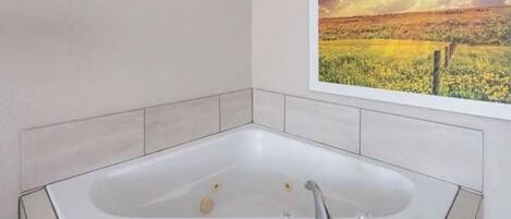 Um banheiro moderno com uma banheira de apoio, uma janela ampla com vista panorâmica e piso revestido de azulejos.