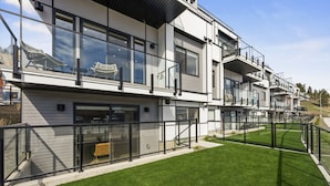A modern multi-story building with large windows, balconies, and a well-maintained lawn.