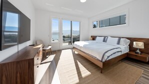 A bedroom with a large bed, a desk, a chair, and a TV.