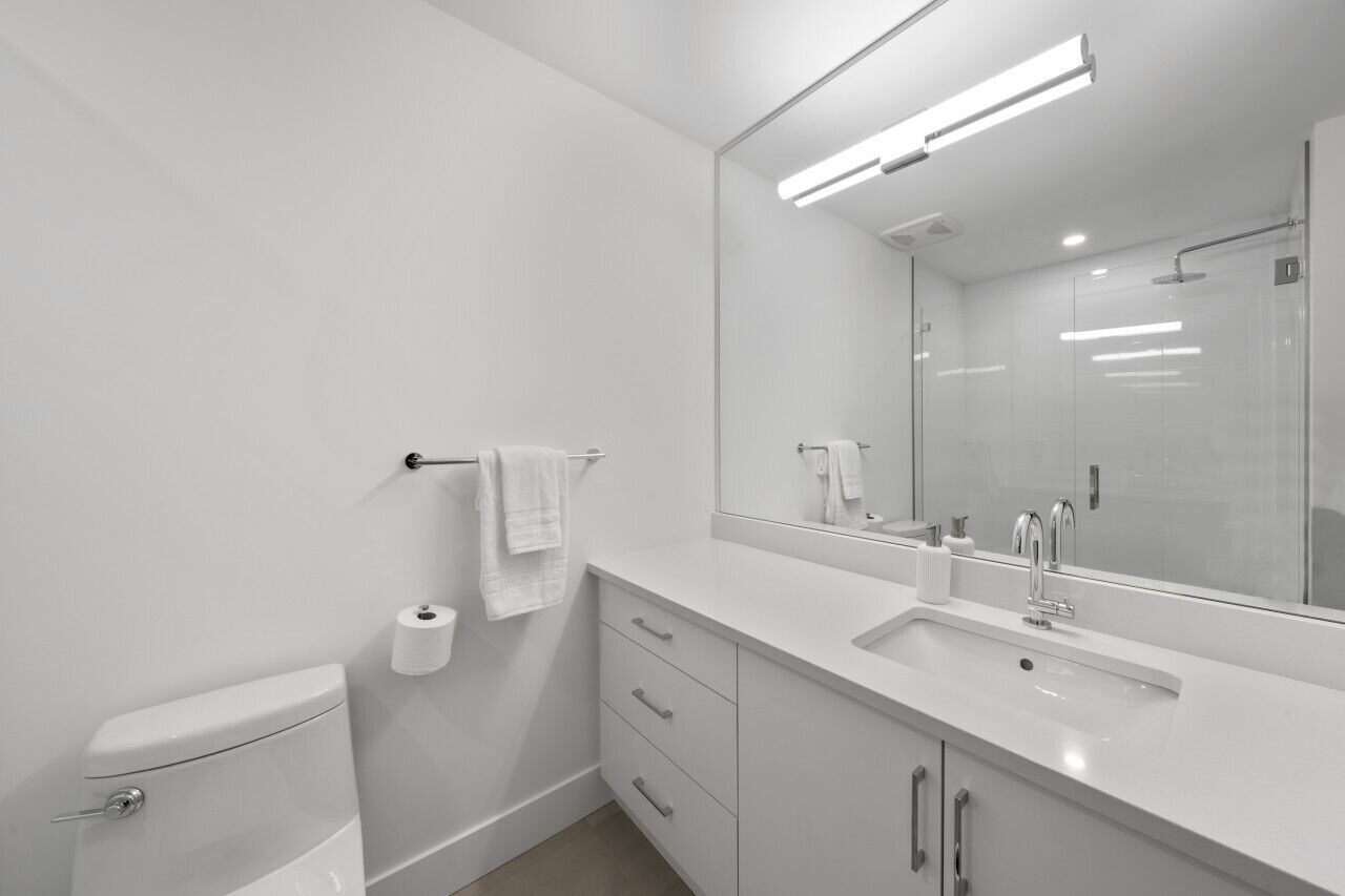 Une salle de bain moderne équipée de toilettes, d’un lavabo, d’un miroir et d’un porte-serviettes.
