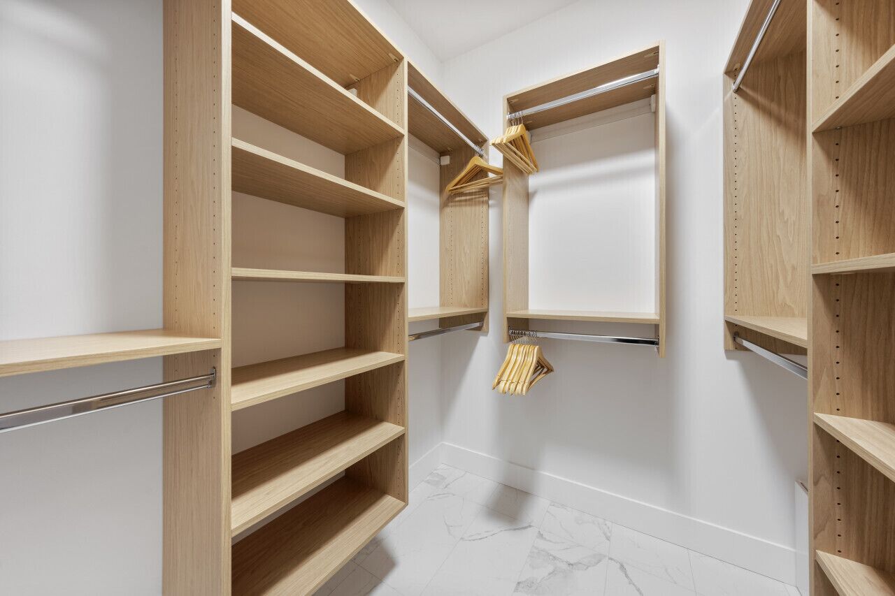 Ein begehbarer Kleiderschrank mit mehreren Holzböden und einer Kleiderstange.