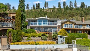 Ein Wohnhaus direkt am Wasser mit mehreren Balkonen, einem Steg und einem Swimmingpool.