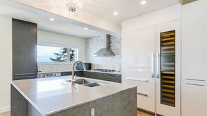 Una cocina moderna con una isla grande, electrodomésticos integrados y vistas al exterior.