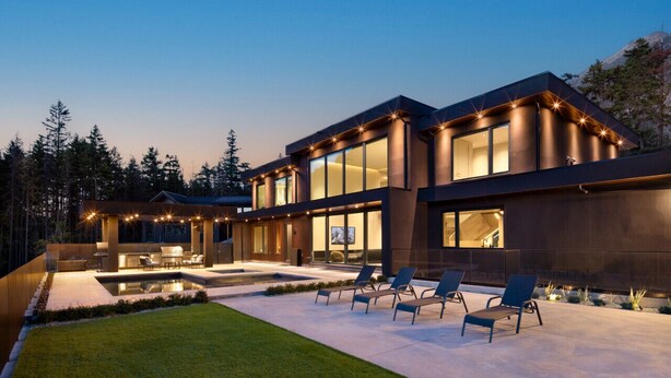 Una casa moderna con piscina, mobiliario de exterior y ventanas amplias.