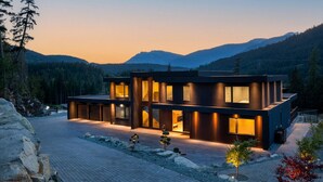 Una casa moderna de dos pisos con amplias ventanas y un exterior bien iluminado.