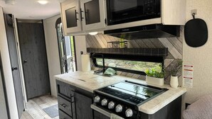 A compact kitchen with a gas stove, microwave, and a small sink.