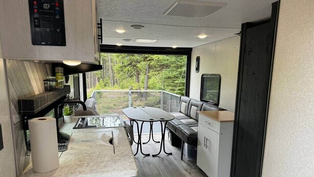 A compact kitchen with a marble countertop, a built-in stove, and a seating area with a table and chairs.