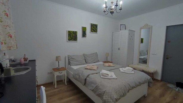 Une chambre à coucher comprenant un lit, des tables de chevet, une armoire, un miroir et un lustre.