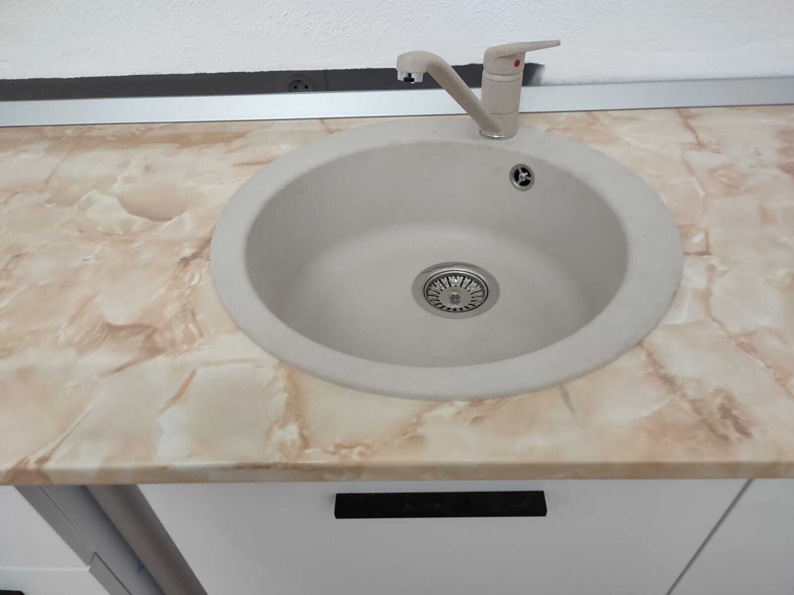 Un lavabo de salle de bain avec un plan de toilette en marbre, un robinet et un drain.