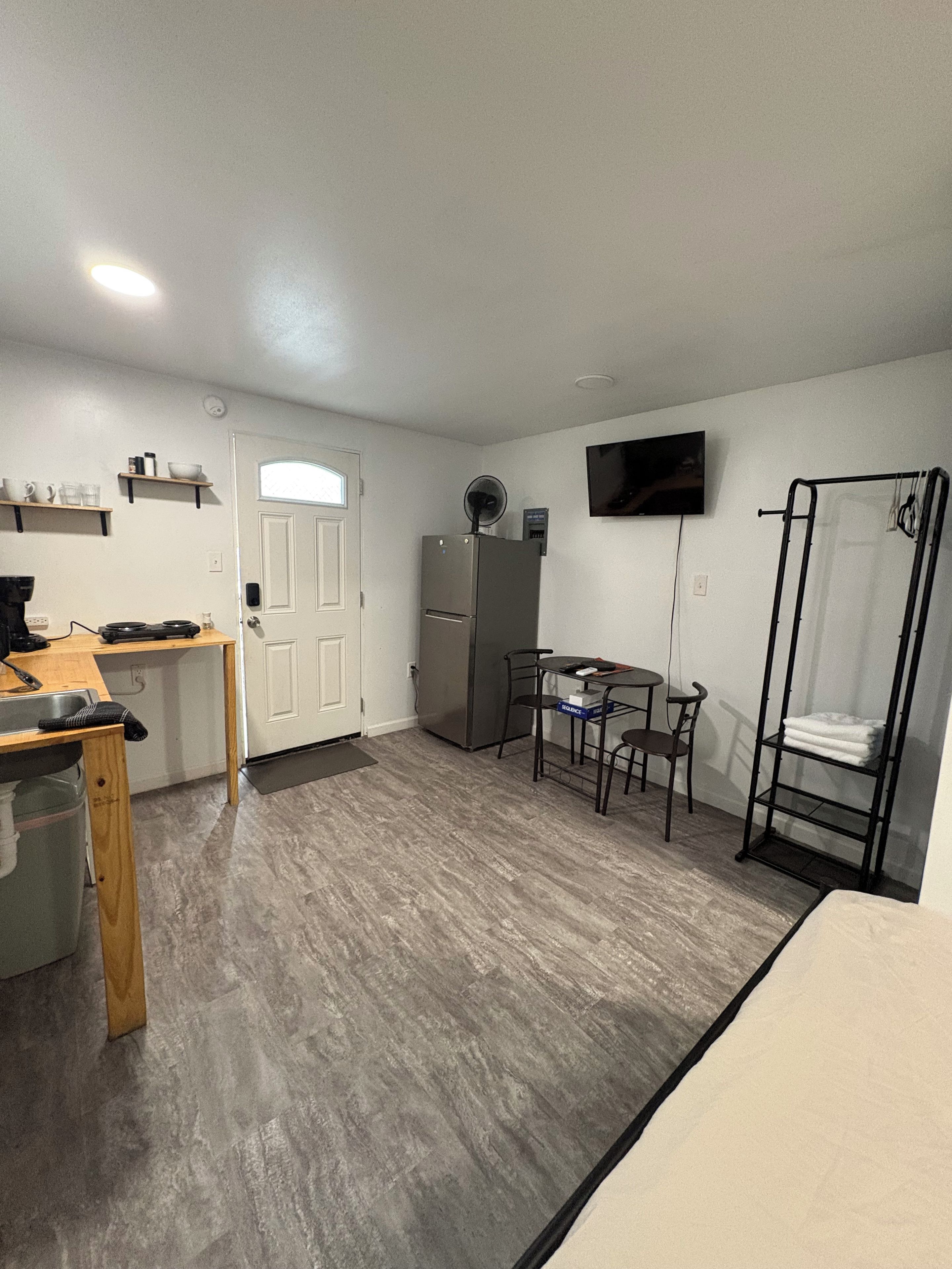 Una habitación compacta con kitchenette, zona de comedor, televisor montado en la pared y estantería empotrada.