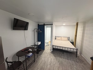 A small, compact room with a bed, a desk, a chair, a TV mounted on the wall, and a clothes drying rack. - Mountain studio in Rocky FaceChattanoogaDalton (Rocky Face)