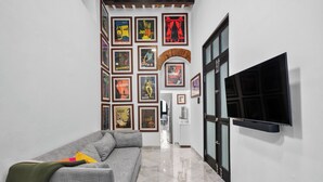 A hallway with a grey sofa, a TV mounted on the wall, and various framed posters on the wall. - Old San Juan Art Loft Fast Wifi Near El Morro (San Juan)