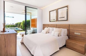 A modern bedroom with a large bed, wooden headboard, and two framed pictures on the wall.