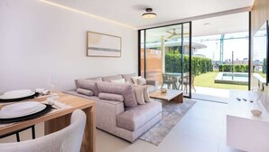 Ein modernes Wohnzimmer mit einer Couch, einem Esstisch und einer Glastür, die auf einen Balkon führt.