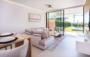 Een moderne woonkamer met een bank, een eettafel en een glazen deur die leidt naar een balkon.