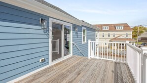 Une maison bleue avec une terrasse en bois et une balustrade blanche.