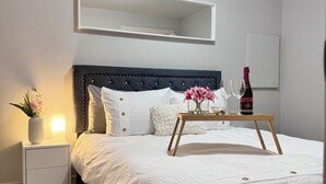 A neatly arranged bedroom with a bed, bedside table, nightstand, and a bedside lamp.