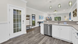 A modern kitchen with white cabinetry, a dishwasher, and pendant lighting. - Holly House / Poolside Getaway / Near the Beach (North Myrtle Beach)