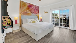 A bedroom with a bed, a ceiling fan, a large window with curtains, and a wall with a colorful abstract painting. - Holly House / Poolside Getaway / Near the Beach (North Myrtle Beach)