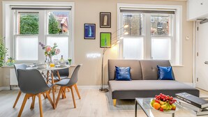 Una sala de estar moderna con un sofá, una mesa de comedor, sillas y una mesa de centro con fruta.