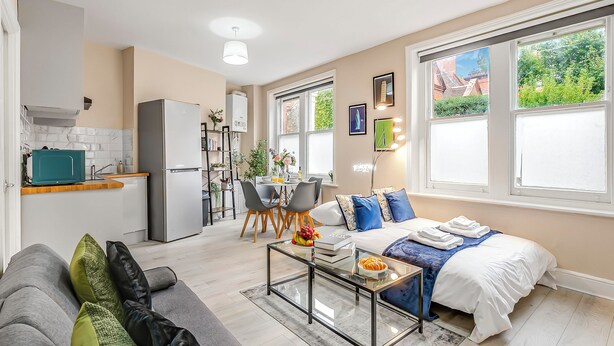 Un apartamento moderno con cocina, comedor y sala de estar. Cuenta con un sofá, una mesa de centro y una cama con vistas al jardín.