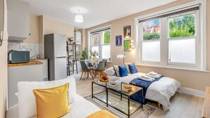 Un apartamento moderno con sala de estar, comedor y kitchenette. Cuenta con ventanas amplias, un sofá, una mesa de centro y una cama.