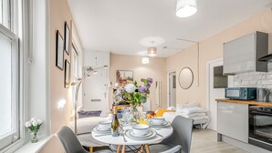 Una cocina moderna con microondas, horno y comedor equipado con una mesa, sillas y un jarrón de flores.