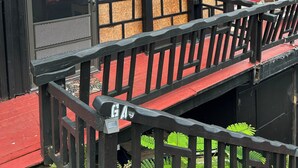 A building with a red roof and black railings, featuring a door with a window and a sign marked "GA". - Shibui Cove (St. Thomas)