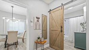 Un interior moderno con zona de comedor, una puerta corredera estilo granero y un baño con cortina de ducha.