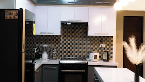 A modern kitchen with grey cabinets, a black refrigerator, a microwave, and a coffee maker. - Experience the ultimate relaxation and privacy in Gray's Farmhouse. (Quezon)