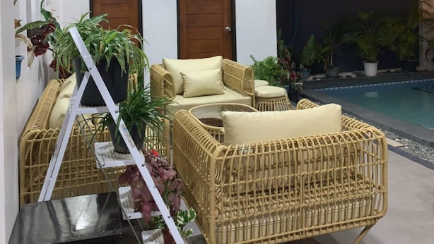 A modern indoor space with wicker furniture, two wooden doors, and a pool area. - Experience the ultimate relaxation and privacy in Gray's Farmhouse. (Quezon)