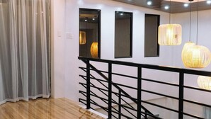 A modern interior with a wooden floor, a staircase with black railings, and pendant lighting. - Experience the ultimate relaxation and privacy in Gray's Farmhouse. (Quezon)