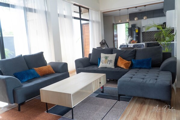 A modern living room with two grey sofas, a wooden coffee table, and a kitchen in the background. - Experience the ultimate relaxation and privacy in Gray's Farmhouse. (Quezon)