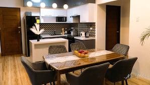 A modern kitchen with a central island, a dining table with chairs, and a refrigerator. - Experience the ultimate relaxation and privacy in Gray's Farmhouse. (Quezon)